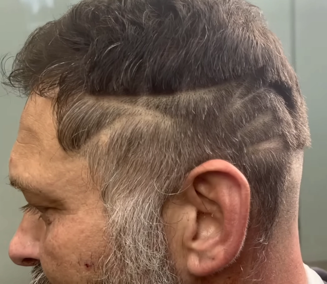 picture of a side profile with an older white guy with shaved segments in his hair