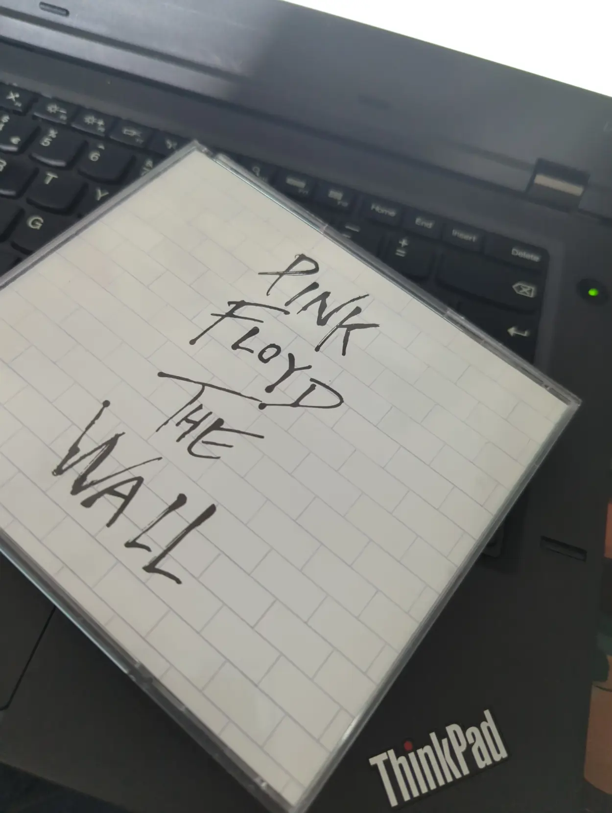 Pink Floyd's The Wall on CD on top of a ThinkPad